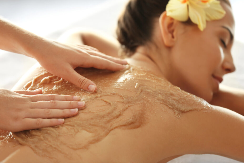 vrouw liggen en de masseuse masseert body scrub op haar rug.