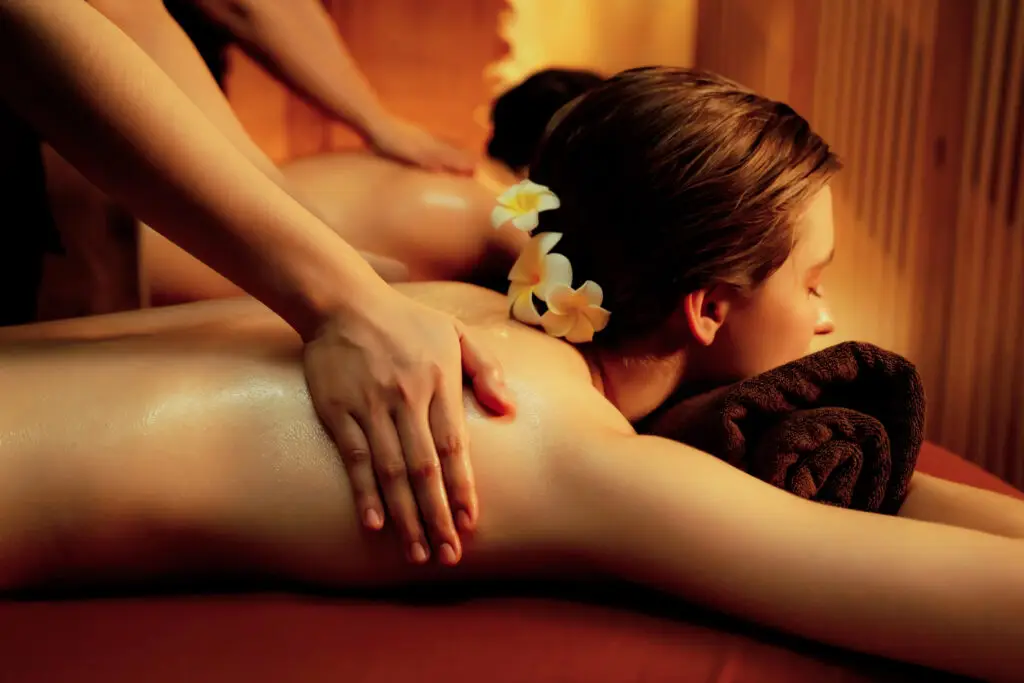 Twee masseuses masseren de ruggen van twee klanten.