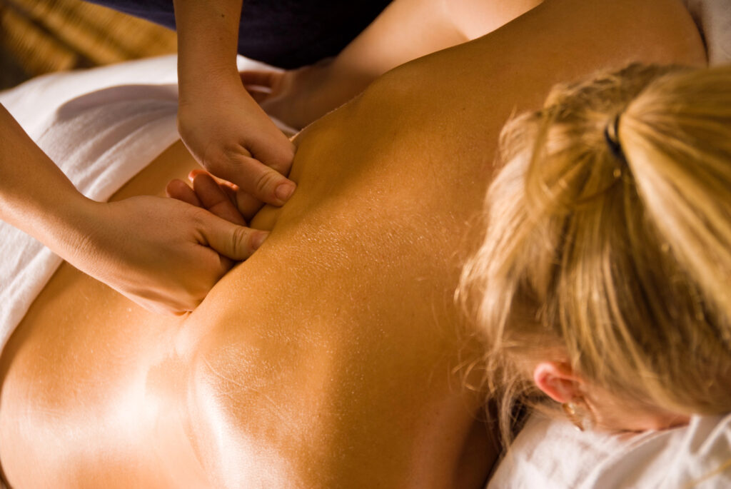 Een masseuse masseert de rug van een vrouw.